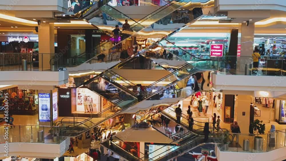 JAKARTA, Indonesia - May 14, 2019: Escalator in luxury shopping mall with crowded visitor and fashion stores view.