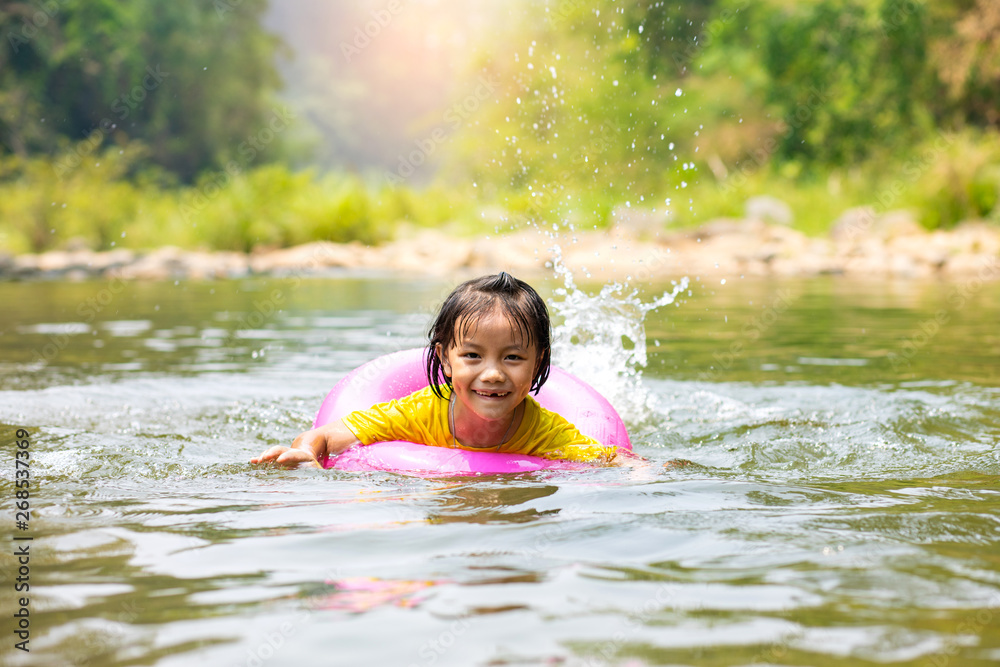 Fototapeta premium Little Asian girl in pool ring swimming in river