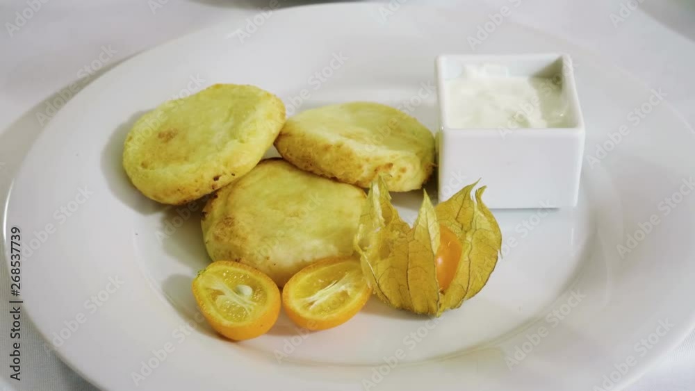 Close-up shot of three cheesecakes, orange, cape gooseberry and sour cream on a white plate. 4K Close-up shot of three cheesecakes, orange, cape gooseberry and sour cream on a white plate. 4K