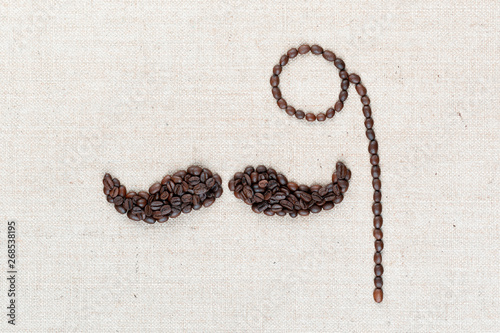 A monocle and a mustache made with coffee beans shot from above, aligned in the center, closeup.