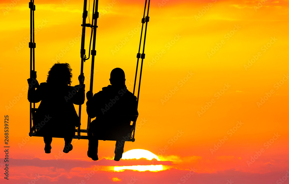 Couple (silhouettes of woman and man) on a seesaw swinging and flying high to sunset. Huge yellow sun disk on a red sky. Inspiration, love and dreams Couple (silhouettes of woman and man) on a seesaw swinging and flying high to sunset. Huge yellow sun disk on a red sky. Inspiration, love and dreams