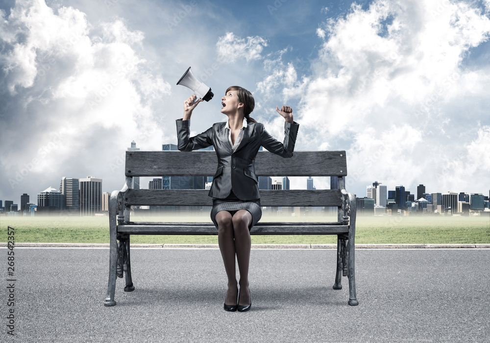Business woman with megaphone on wooden bench Business woman with megaphone on wooden bench
