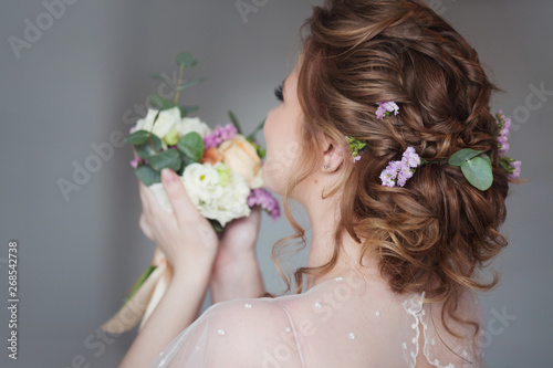 Beautiful and elegant wedding hairstyle. Young bride with bouquet of flowers