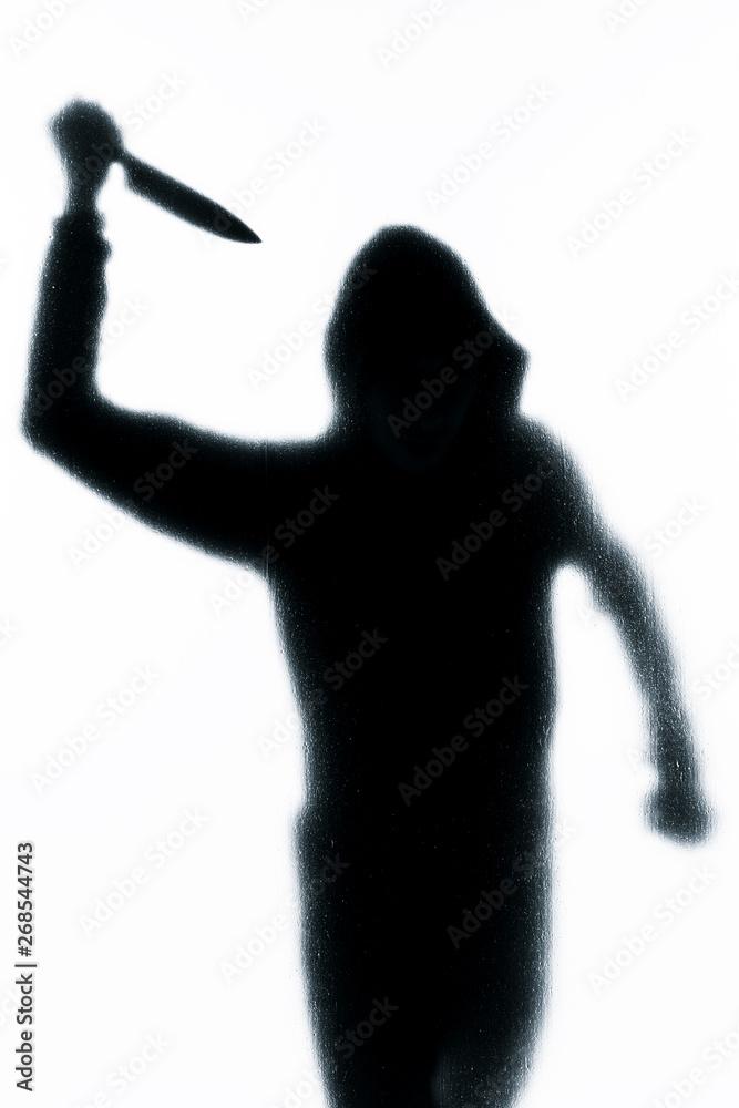 Dangerous man behind frosted glass with a knife in his hand. Halloween. Black and white image. Dangerous man behind frosted glass with a knife in his hand. Halloween. Black and white image.