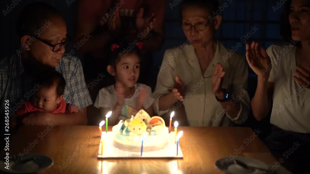 Slow motion footage of Happy birthday party of grandfather and little nephew in the middle. Everyone sing happy birthday song and clap hands for them before they blow the candle. Happy family activity
