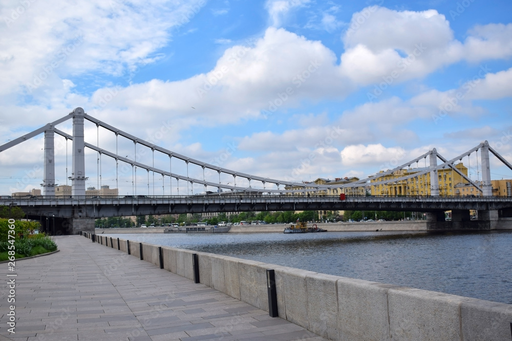 Fototapeta premium Moscow, Russia - May 13, 2019: Crimean Bridge (Krymsky Most) across the Moskva river against the blue cloudy sky. The view from the embankment