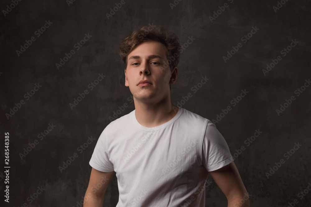 Handsome young man with a stylish haircut in a white shirt on black background looking at camera. Handsome young man with a stylish haircut in a white shirt on black background looking at camera.