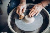 Wrinkled hands wizard on potter wheel makes clay dishes. Place to work