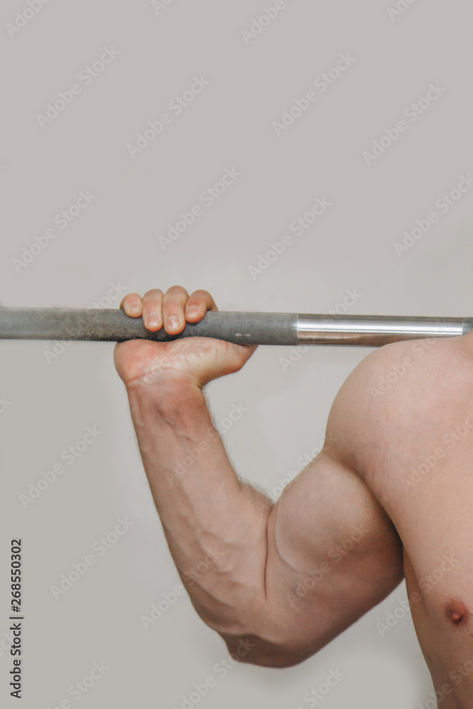 athlete with big hands holding a barbell bar in the training center. training tools in the gym close-up