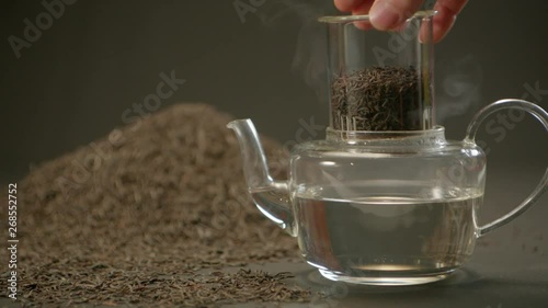 Tea infusers in glass teapot with side tea leaves. Camera pan. Alexa Plus