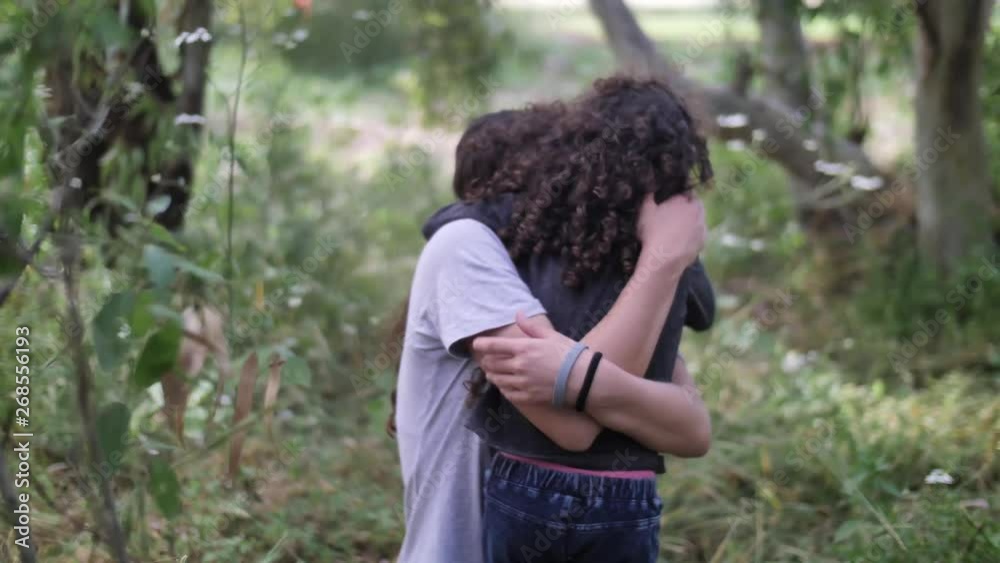 Two girls hug in nature. Older sister takes younger in arms Two girls hug in nature. Older sister takes younger in arms
