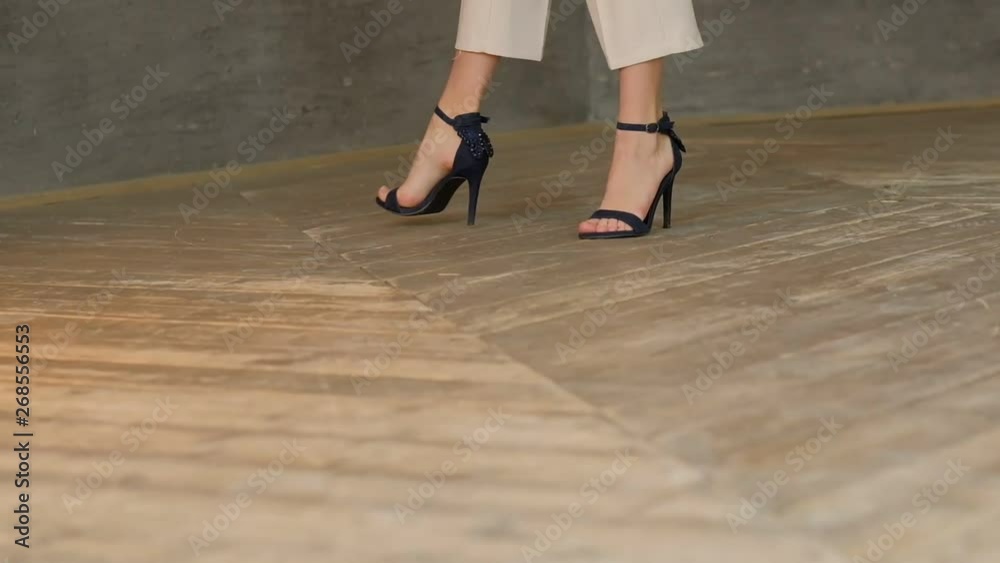 Tracking with low-section of silhouette of female legs in high heels shoes walking wooden parquet, littered horizon. slow motion shot Tracking with low-section of silhouette of female legs in high heels shoes walking wooden parquet, littered horizon. slow motion shot