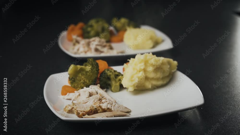 Large wooden spoon puts a dollop of steaming hot mashed potatoes on plates for dinner. Side dishes with a meal of roast chicken. Large wooden spoon puts a dollop of steaming hot mashed potatoes on plates for dinner. Side dishes with a meal of roast chicken.