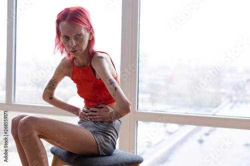 Woman with anorexia sitting near the window feeling awful