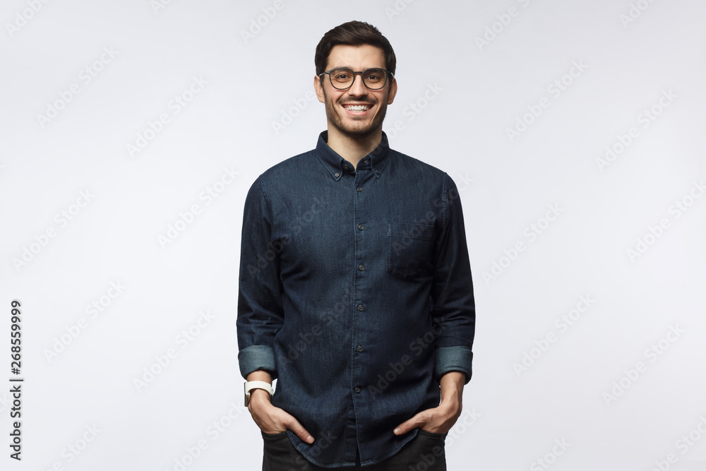 Obraz premium Handsome smiling european guy in casual denim shirt standing against white background