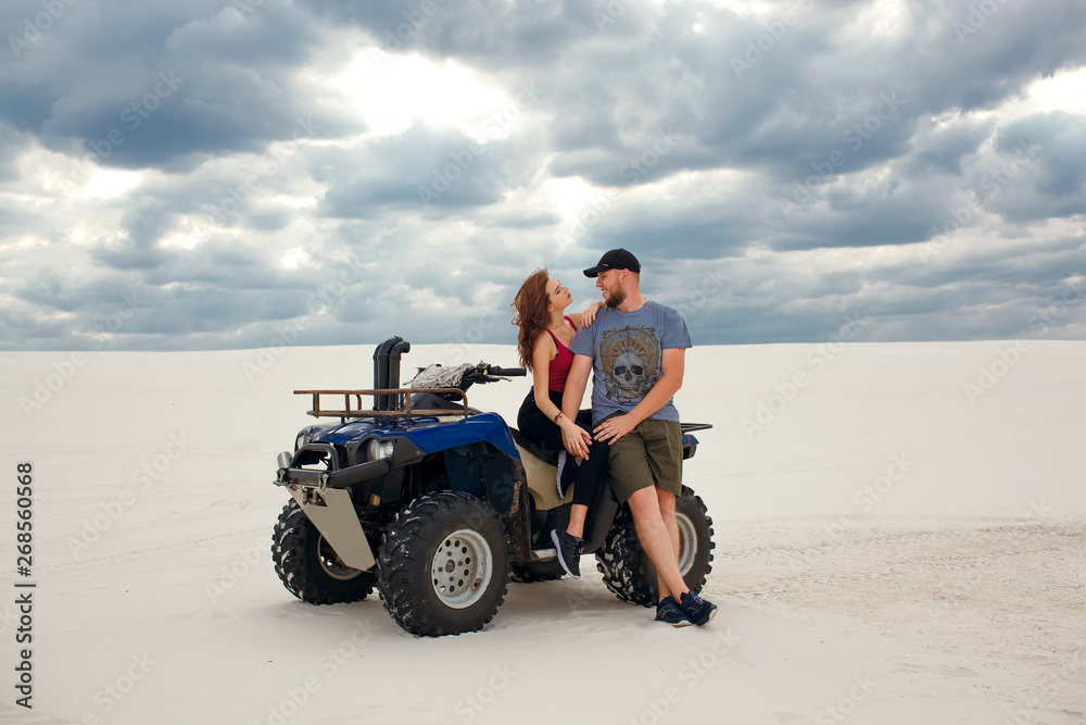 Obraz premium girl hugs her boyfriend on a quad in the desert, a loving couple enjoys each other