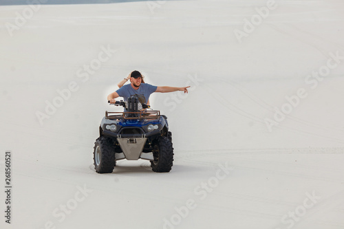 The guy and the girl ride a quad bike in the desert, having fun and enjoying, a couple of lovers photo