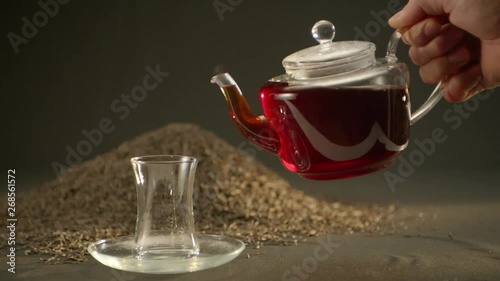 Pouring tea into the cup with teapot and tea leaves at the background. Alexa Plus Camera Slow Motion.