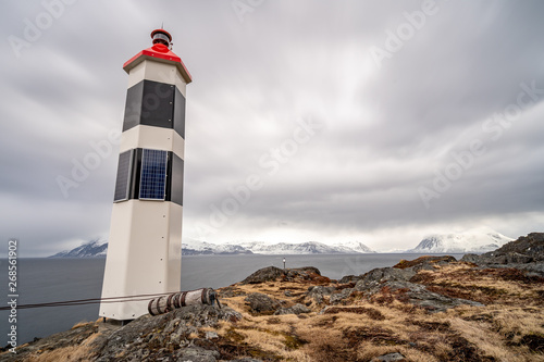 Black and white lighthouse in norwegian fjord.