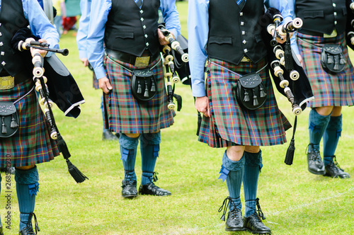 Bagpipers wearing kilts marching while carrying their bagpipes