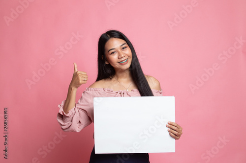 Young Asian woman show thumbs up with white blank sign.