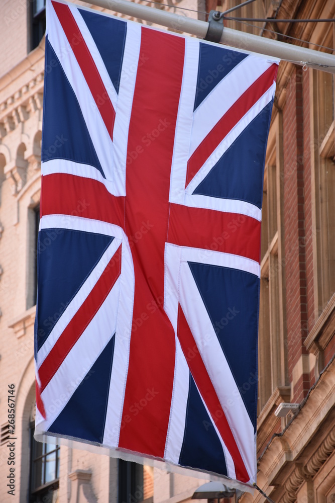 Fototapeta premium waving UK flag in the blue sky, Union Jack flag 