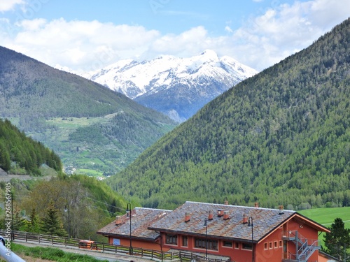 A snow capped peak in the Alps rising majestically above lesser peaks with houses in the foreground