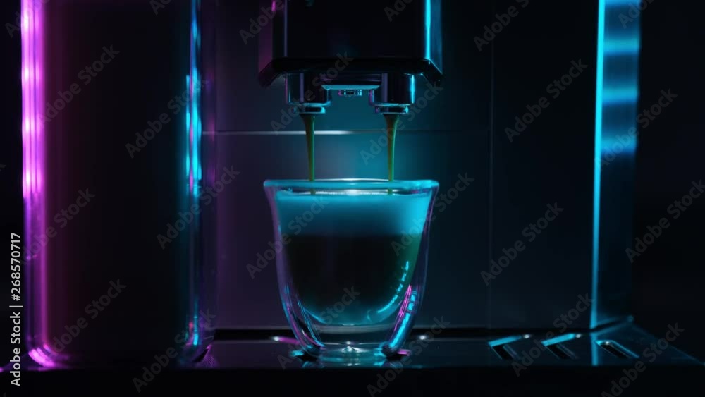 Coffee machine makes coffee with milk. Coffee machine with a cup of hot cappuccino coffee. Maker with cup of  coffee with milk. Real time footage. Art concept. Fluorescent colors.
