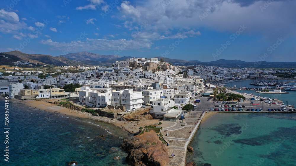 Fototapeta premium Aerial drone photo of iconic chora, main town of Naxos island featuring beautiful uphill castle views to the Aegean deep blue sea and Temple of Apollon at the background, Cyclades, Greece