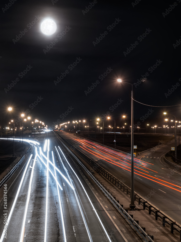 Night city traffic with the bright full moon in the foggy sky