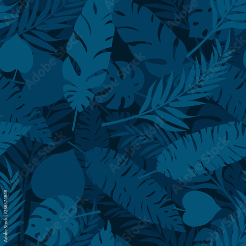Seamless pattern made with blue and grreen silhouettes of tropical leaves on dark blue background. Tropic folage texture.Vector flat illustration photo