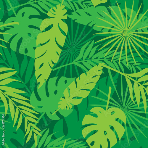 Seamless pattern made with green and yellow silhouettes of tropical leaves on dark green background. Tropic folage texture.Vector flat illustration photo