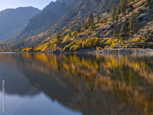 Autumn landscape with clear mountain lake and golden trees mirror reflection