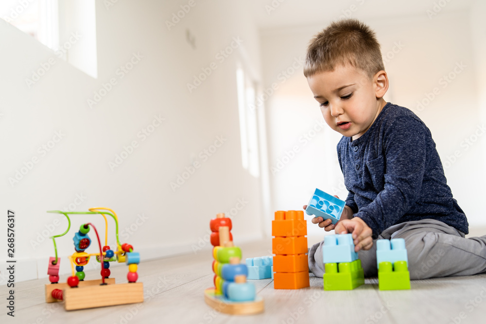 Small boy playing with little brick block toys at home on the floor having fun Small boy playing with little brick block toys at home on the floor having fun