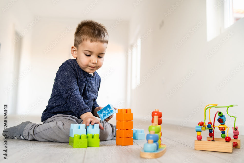 Small boy playing with little brick block toys at home on the floor having fun Small boy playing with little brick block toys at home on the floor having fun