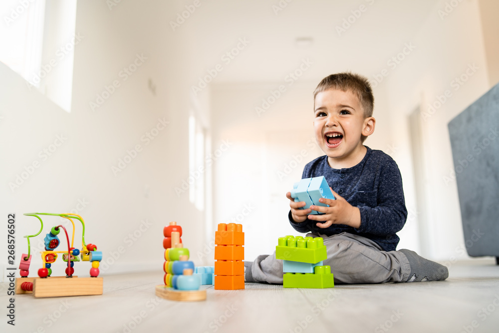 Small boy playing with little brick block toys at home on the floor smiling Small boy playing with little brick block toys at home on the floor smiling