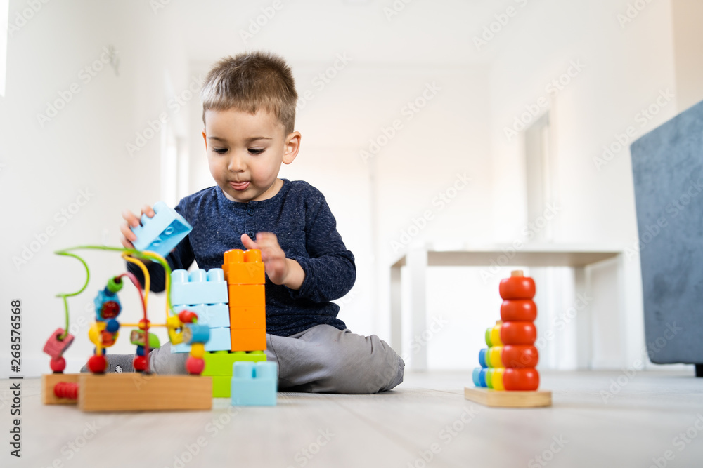 Small boy playing with little brick block toys at home on the floor Small boy playing with little brick block toys at home on the floor