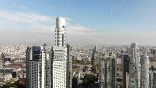 Aerial view of the skyscrapers in Puerto Madero, Buenos Aires with the city skyline as background on a clear day. Drone slowly ascending while rotating photo