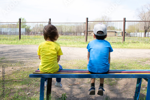 Fototapeta Naklejka Na Ścianę i Meble -  girl and boy sitting on bench, looking at park
