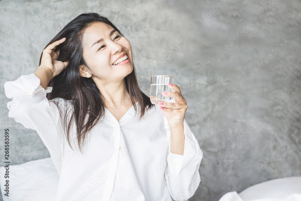 happy Asian woman drinking fresh water in bed after wake up in the morning happy Asian woman drinking fresh water in bed after wake up in the morning