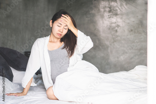 pregnant Asian woman wake up unwell and feeling sick in the morning sitting on bed
