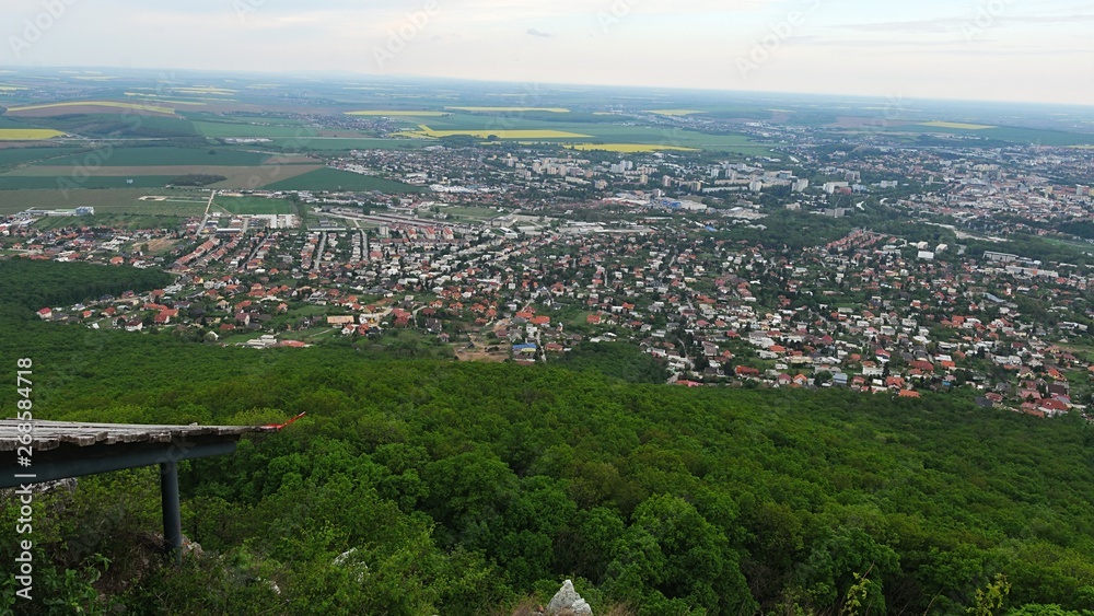 Obraz premium View of center of Nitra city, western Slovakia, from Zobor hill located above the city, cloudy spring day, remains of aircable landing zone in right bottom corner