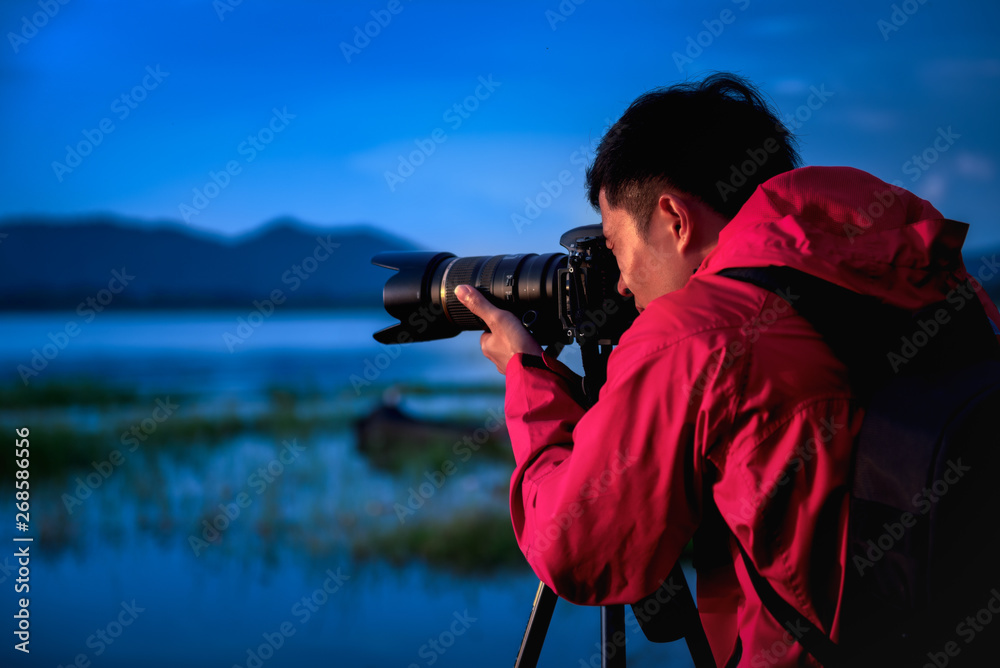 Travel photographer taking a photo with nature the lake in sunset to nightlife with camera on tripod, Focusing attention nature mountain view and lake,  Natural photography relaxing concept.