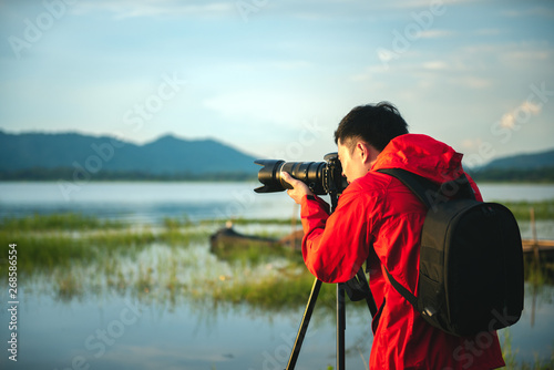 Travel photographer taking a photo with nature the lake in sunset with camera on tripod, Focusing attention nature mountain view and lake, Natural photography relaxing concept.