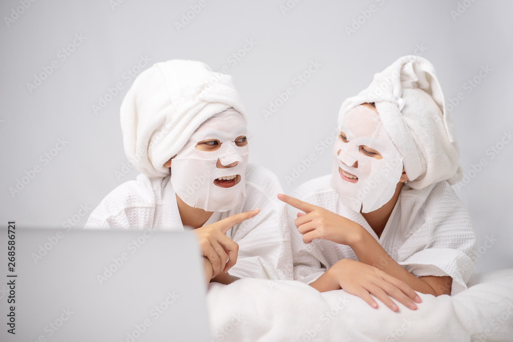 2 Young woman wrapped hair with towel while having fun with homemade facial mask. Beauty treatment process of aging for rejuvenation. Skin Restoration Whitening, Moisturizing, Brightening. 2 Young woman wrapped hair with towel while having fun with homemade facial mask. Beauty treatment process of aging for rejuvenation. Skin Restoration Whitening, Moisturizing, Brightening.