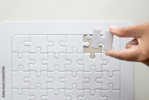 Hands women putting jigsaw puzzle white color,Puzzle pieces grid,Concept partnership business successful teamwork,Top view,Copy space for text