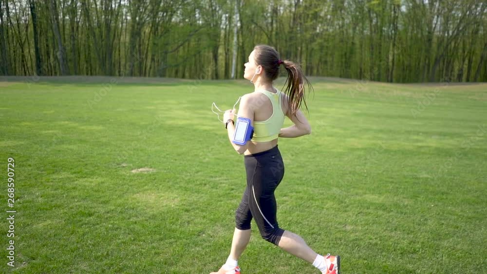 Slow motion. Adult fitness woman runner run on green field. Steady shot Slow motion. Adult fitness woman runner run on green field. Steady shot