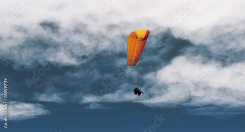 Two paraglider tandem fly against the blue sky,tandem paragliding guided by a pilot