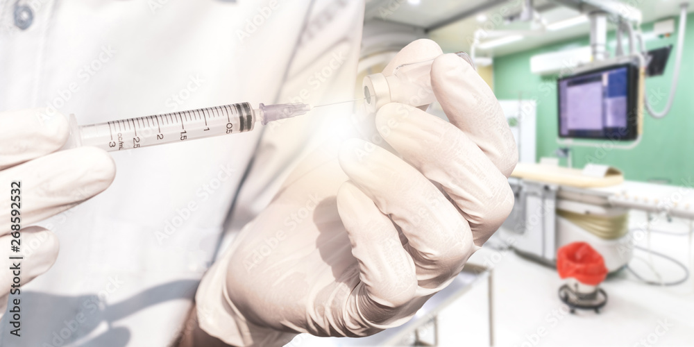 Doctor hand holding vials medication and injection needle. Digital Subtraction Angiography Room, operating room with X-ray medical scan in hospital. Doctor hand holding vials medication and injection needle. Digital Subtraction Angiography Room, operating room with X-ray medical scan in hospital.