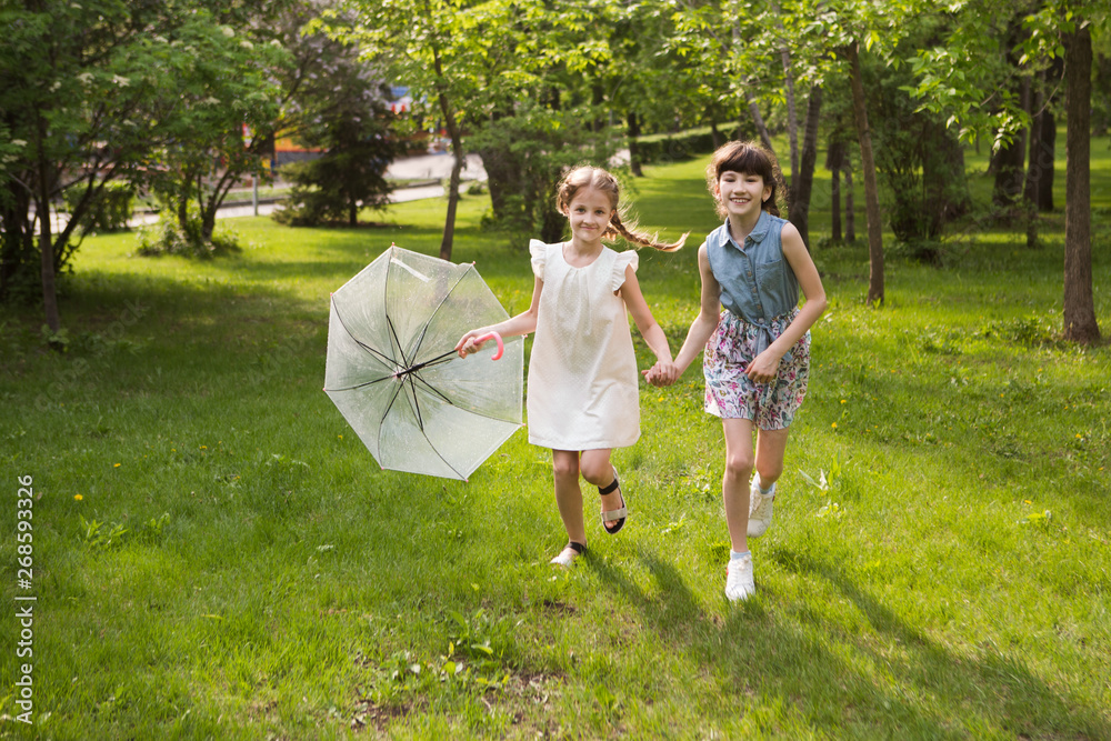 Fototapeta premium little girls with an umbrella playing out in the rain in the summer outdoors